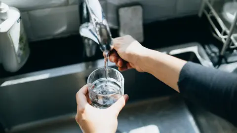 Getty Images A person filling a glass with water from a kitchen tap.