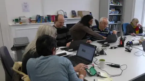 A group of men and women looking at computer screens in a classroom
