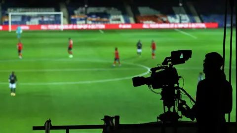 A camera operator filming a football match