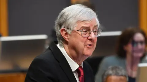 PA Media Mark Drakeford wearing a dark suit and red tie.