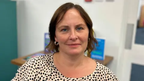 Corrine Hunter, who has short brown hair and blue eyes. She is smiling in the photo.