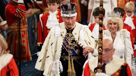 King Charles and Queen Camilla in royal robes and crowns at the Kings speech ceremony