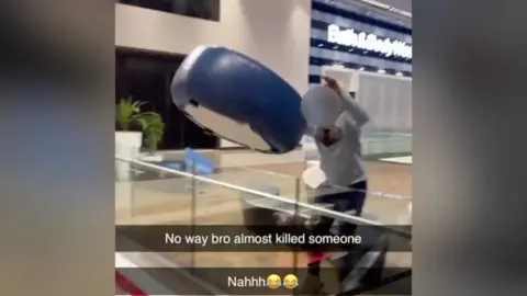 A boy throws a stool off a balcony at a shopping centre