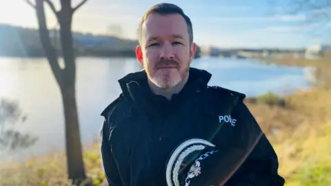 Police officer in black uniform and looking at the camera