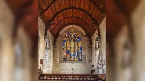 St John's Church A view of the whole east window in an otherwise plain chapel with unadorned stone walls and a wooden roof