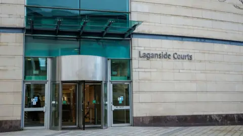 PA Media The entrance of Laganside Courts which house Belfast Crown Court. The brick building is a sand colour.