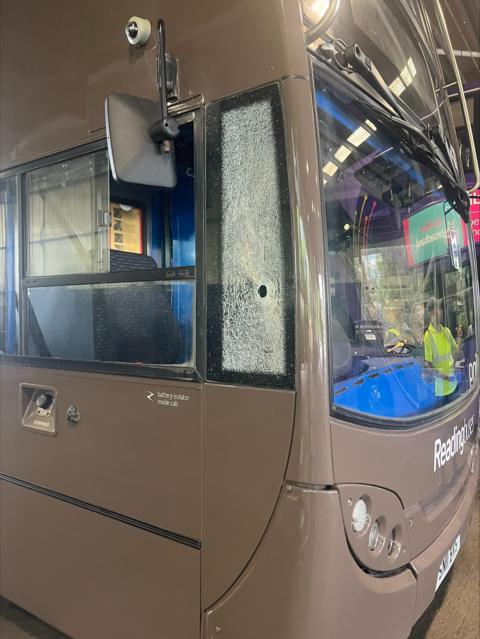 The front of a Reading Bus with the window next to its cockpit shattered, with a noticeable hole (about the size of a nut) 