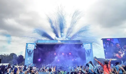 Coventry City Council Blue fireworks go off behind the stage at the Memorial Park event