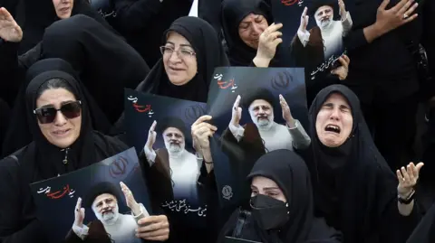 Mourners holding pictures of the late president