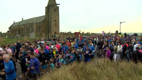 Hundreds of people are running as a group past a church