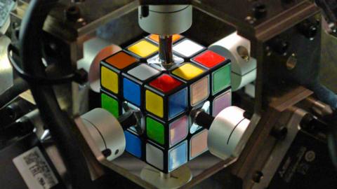 close up of rubik's cube with robot arms connected to its different sides
