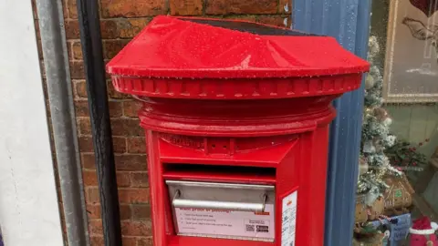 Syston Town News Red solar-powered post box on High Street outside Syston Post Office, in Leicestershire.