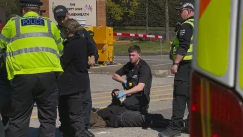 Zoie O'Brien/BBC A person on the floor with a police officer on top of them during an arrest. Other police officers who have their backs to the camera and also appear to be arresting someone are in the image. 
