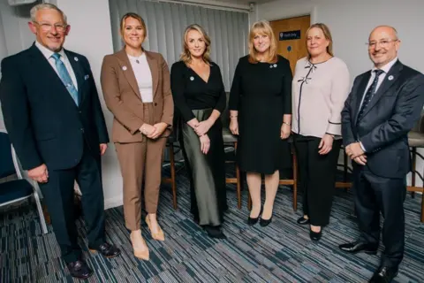 Supplied Two men and four women stood in front of the camera. 