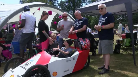 Alex Watts on the right with other members of his team gathered around the white and read kart