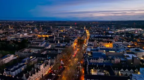 Aerial establishing shot of Oxford, England, flying over the city centre buildings and the colleges and libraries of the famous university.