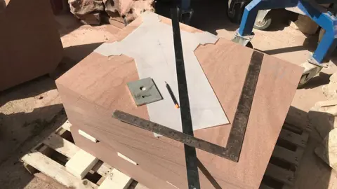Large pieces of stone with cross template on top before it is carved by a stonemason