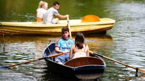 PA Media Two couples in blue and yellow rowing boats