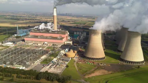 A view of Cottam Power Station from a high vantage point. There are grids to the left and cooling towers to the right.
