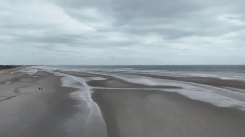 BBC West Wittering beach at low tide. The sky is overcast.