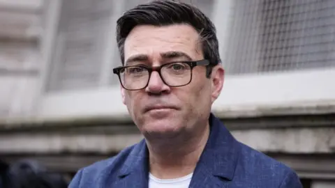 PA Media Andy Burnham has a blue jacket and white T-shirt and has dark glasses