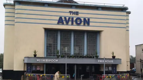 BBC The Avion pub. A beige gathering  with The Avion successful  navy lettering. Lower down   it says Wetherspoon and Free House