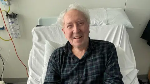 BBC Man in a hospital bed smiling. 