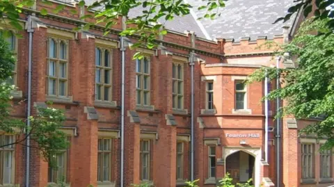 The exterior of Fearon Hall, a red-brick two-storey building with large stone framed windows.