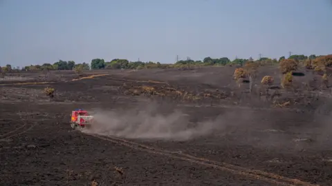 DWFRS A picture that shows large areas of damage after the fire and a fire service vehicle driving across the scorched land.