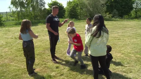 Man teaching children outside on the grass