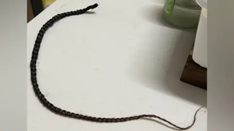 A long, black hair braid on a counter top.