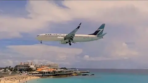 A plane flying low over a beach 
