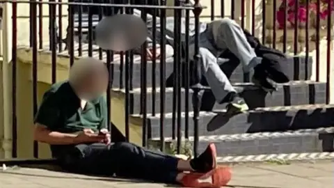 Supplied Two men slumped on steps outside a house.