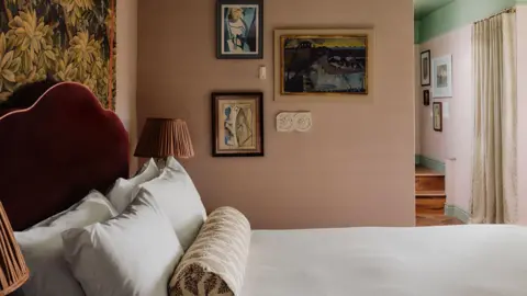 The Netty A made up bed in a room with cream walls and a green ceiling.