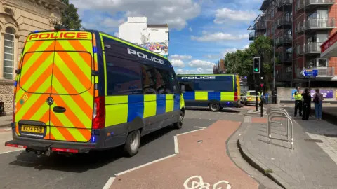 Two large police vans parked in the middle of the road.