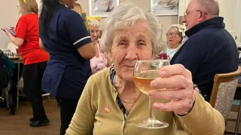 Hilda Jackson holding up a glass of wine to the camera