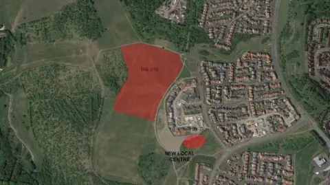 A map showing the proposed site in red which is surrounded by fields and trees.
A housing development can be seen to the right of the site.