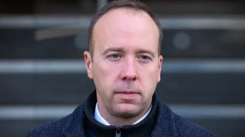 Getty Images Former Health Secretary Matt Hancock looks pensive as he leaves the Covid Inquiry after giving evidence. He wears a white shirt, black zip up sweater and a grey jacket. 