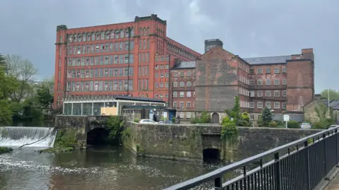 An old brick mill by a river. 