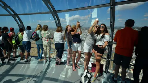 Glyn Kirk/Getty Images Visitors smile, look at the view and take pictures in Brighton's i360 tower