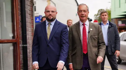 PA Media Reform UK leader Nigel Farage (centre right) campaigning in Caerphilly, South Wales, with his party's candidate, Llyr Powell (left), for the upcoming Caerphilly Senedd by-election