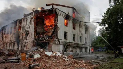 Reuters Firefighters attempt to put out a blaze at a building hit by a Russian drone strike