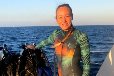 Survivors inform BBC of terrifying escapes Hissora Gonzalez Hissora Gonzalez standing on a boat at sea in a green and orange wetsuit.