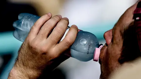 Man drinks from a cold bottle of water