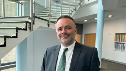 Northampton College Jason Lancaster in a suit with a green tie