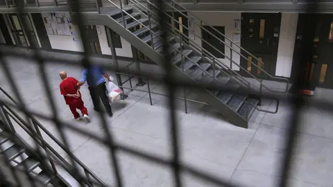 A guard escorts an immigrant detainee from his 'segregation cell' back into the general population at the Adelanto Detention Facility on November 15, 2013 in Adelanto, California.