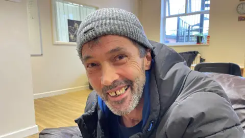 David is wearing a woolly hat and smiling