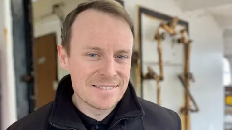 Philip smiles for the camera onboard the Royal Iris. He has short brown hair.