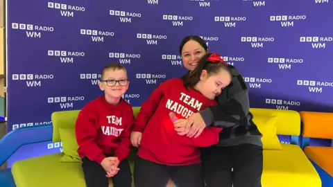 Cleo with her mum Lisa and brother Louis. They are sat on the BBC Radio WM sofa. 