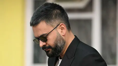 Getty Images Balen Shah wears dark sunglasses and a dark jacket and white T-shirt